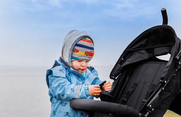 Toddler girl examining safety belt and buckle of buggy