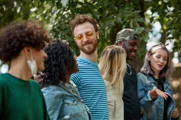 american mixed race youth spend time together in the park, friendly men and women have fun, laugh. international love, friendship, tolerance concept