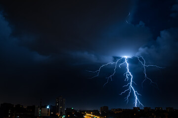 Naklejka na ściany i meble Bright flash of powerful lightning in the city at nighttime.