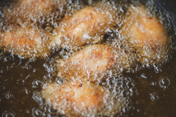 Frying salt chicken wing with cooking oil.