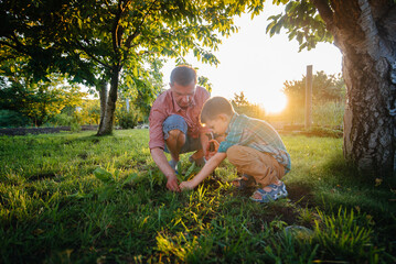 Little brother and sister are planting seedlings with their father in a beautiful spring garden at sunset. New life. Save the environment. Careful attitude to the surrounding world and nature