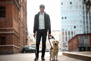 20-25 years old eyeless man with guide dog in city streets, walk in city streets, help, assist...