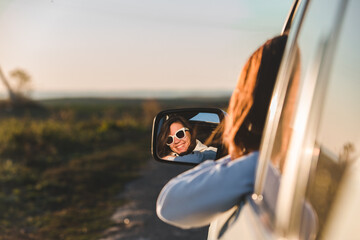 gorgeous woman in sunglasses reflection in car mirror on sunset
