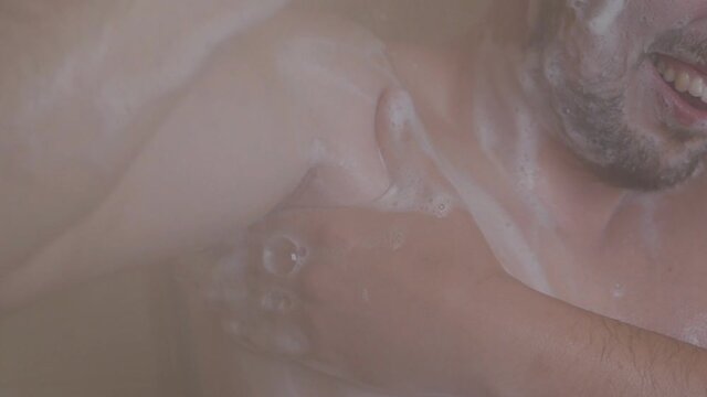 A man washes his armpits in the shower and is uncomfortable due to irritation of the armpits after shaving, he stands soaped, in the shower, under running water