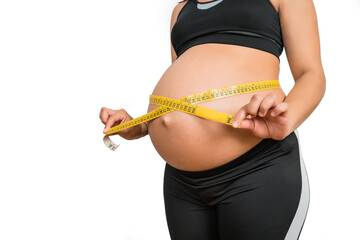 Pregnant woman using measuring tape to check baby development.
