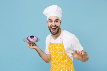 Cheerful young bearded male chef or cook baker man in apron white t-shirt toque chefs hat isolated on blue wall background studio portrait. Cooking food concept. Mock up copy space. Hold dessert cake.