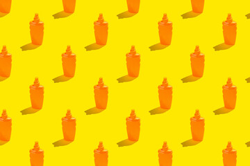 Summer vacation minimal concept. Pattern of orange sunscreen lotion bottles on bright yellow background