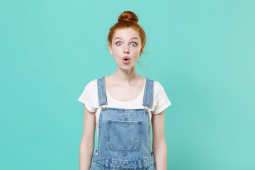 Shocked young readhead girl in casual denim clothes posing isolated on blue turquoise background...