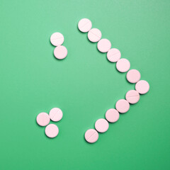 Close up of many white pills on green background.