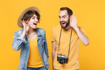 Curious tourists couple friends guy girl in hat with photo camera isolated on yellow background....