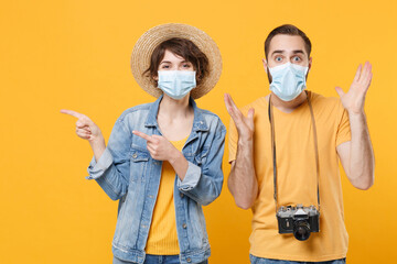 Tourists couple friends guy girl in sterile face mask isolated on yellow background. Epidemic...
