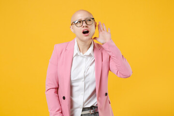 Curious bald business woman in white shirt pink jacket glasses isolated on yellow background...