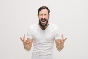 Young handsome man wearing casual white t-shirt over white isolated background crazy and mad shouting and yelling with aggressive expression