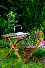 Cup of tea and laptop computer on a wooden table in a garden
