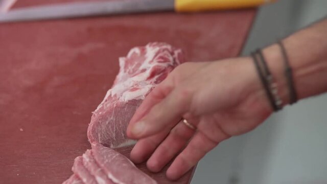 Carnicero cortando filetes de una pieza de lomo de cerdo , en una carniceria de san fernando ,cadiz