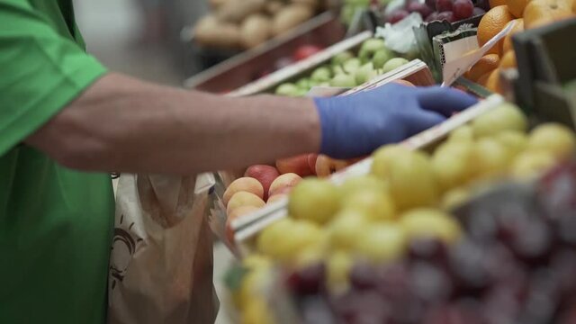Expositor de verduras y frutas en un mercado de cadiz cogiendo fruta para venderlas