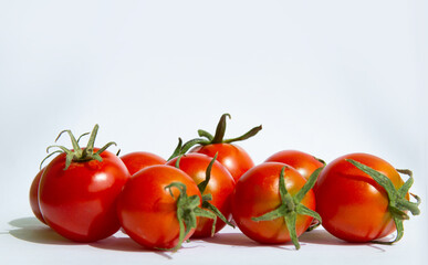 Red cherry tomatoes with green stems on a white background, arranged in a group.copyspace for text