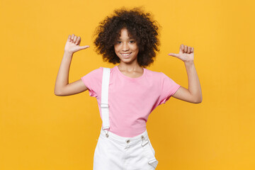 Smiling little african american kid girl 12-13 years old in pink t-shirt isolated on yellow...