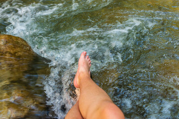 A first person / POV shot of Caucasian female legs in a mountain river Roudoule in the French Alps (Puget-Theniers, Alpes-Maritimes, France)