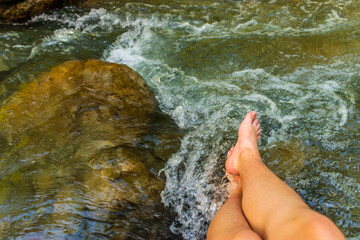 A first person / POV shot of Caucasian female legs in a mountain river Roudoule in the French Alps (Puget-Theniers, Alpes-Maritimes, France)