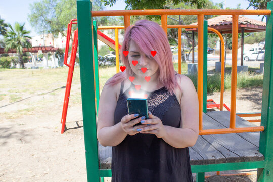 Woman Using Social Networks On Her Cell Phone With Hearts Coming Out Of The Screen