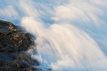 Wasser ist fließend und strömend an Fels mit Sonnenlicht