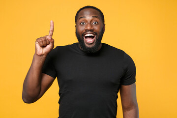 Excited african american man guy football fan in casual black t-shirt isolated on yellow background...