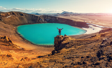Incredible nature landscape of Iceland. Happy traveler, raise hand up on sunset sky, over the Viti...
