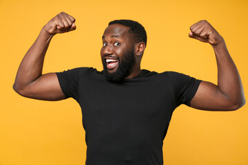 Funny african american man guy football fan in casual black t-shirt isolated on yellow wall...