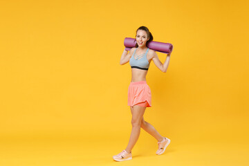Fototapeta na wymiar Full length portrait of cheerful young fitness woman girl in sportswear posing working out isolated on yellow background studio portrait. Workout sport motivation lifestyle concept. Hold yoga mat.
