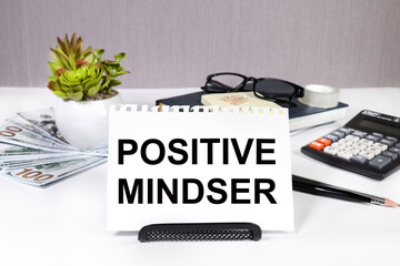 POSITIVE MINDSER word on a white sheet on the background of a calculator, notepad, money.