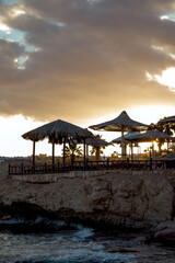 Egypt's luxurious sunset sun with umbrellas and palm trees on the horizon. Beautiful view from the Red Sea in the part of the hotel. Colorful background.