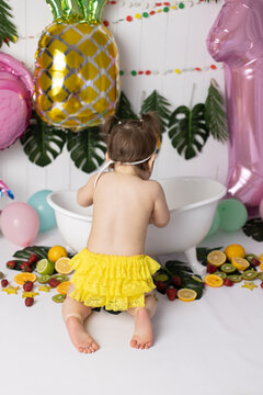 photo zone in the style of tropics and fruits. a small child is sitting at the children's bath with his back