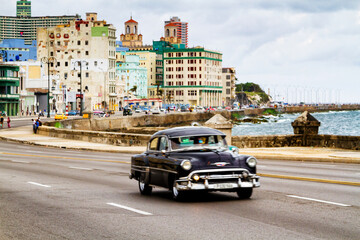 HAVANA, CUBA - NOVEMBER 15, 2017: Old classic vintage cars drive in traffic along famous Malecon avenue in central Havana - the capital of Cuba.