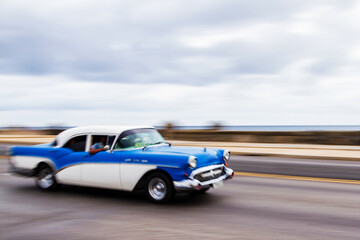 HAVANA, CUBA - NOVEMBER 15, 2017: Old classic vintage cars drive in traffic along famous Malecon avenue in central Havana - the capital of Cuba.