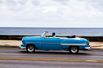 HAVANA, CUBA - NOVEMBER 15, 2017: Old classic vintage cars drive in traffic along famous Malecon avenue in central Havana - the capital of Cuba.
