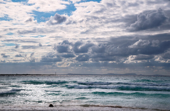 Stormy dark clouds above the sea with sandy beach and curling waves