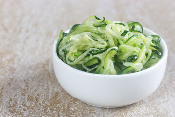 Homemade roasted zucchini spaghetti in white bowl.
