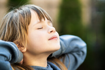 Portrait of young pretty child girl with long hair enjoying warm sunny day in summer outdoors. Cute...