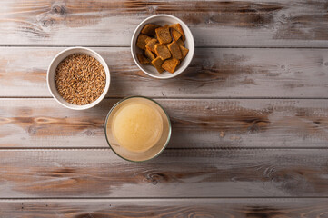 Top view homemade tradishional russian light rye kvass in glass and crackers on wooden background. Wonderful healthy refreshing drink for summer