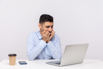Nervous scared man employee sitting office workplace, looking worried anxious at laptop screen and biting nails, panicking of deadline, troubles at work. studio shot isolated on white background