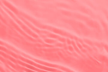 Closeup of pink transparent clear calm water surface texture with splashes and bubbles. Trendy abstract summer nature background. Coral colored waves in sunlight.