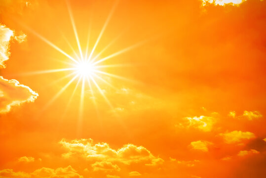 Hot summer or heat wave background, orange sky with clouds and glowing sun