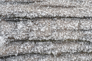 Background of part old wooden bench surface covered with hoarfrost, frost, morning sunlight. Rime. Late fall. Copyspace.