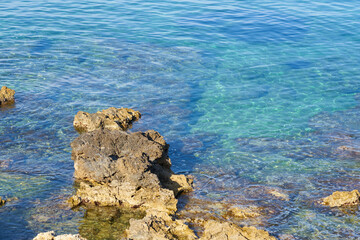 Turquoise surface of waving water in sunshine on tropical rocky beach in Crete, Greece. Copy space.