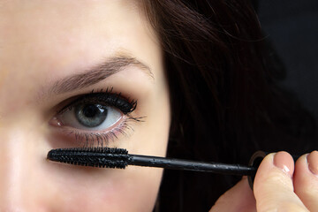 beautiful girl paints eyes with mascara close-up. cosmetics, personal care