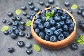 Bowl of fresh ripe sweet juicy blueberries with leaves, summer berries harvest, selective focus