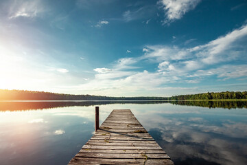 Wooden pier on the background of a beautiful lake summer dawn landscape. Copy space.