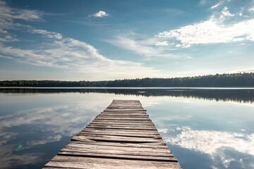 Wooden pier on the background of a beautiful lake summer dawn landscape. Copy space.