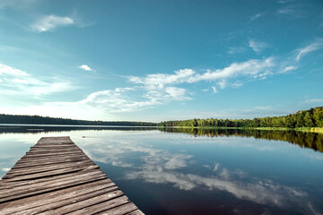 Wooden pier on the background of a beautiful lake summer dawn landscape. Copy space.